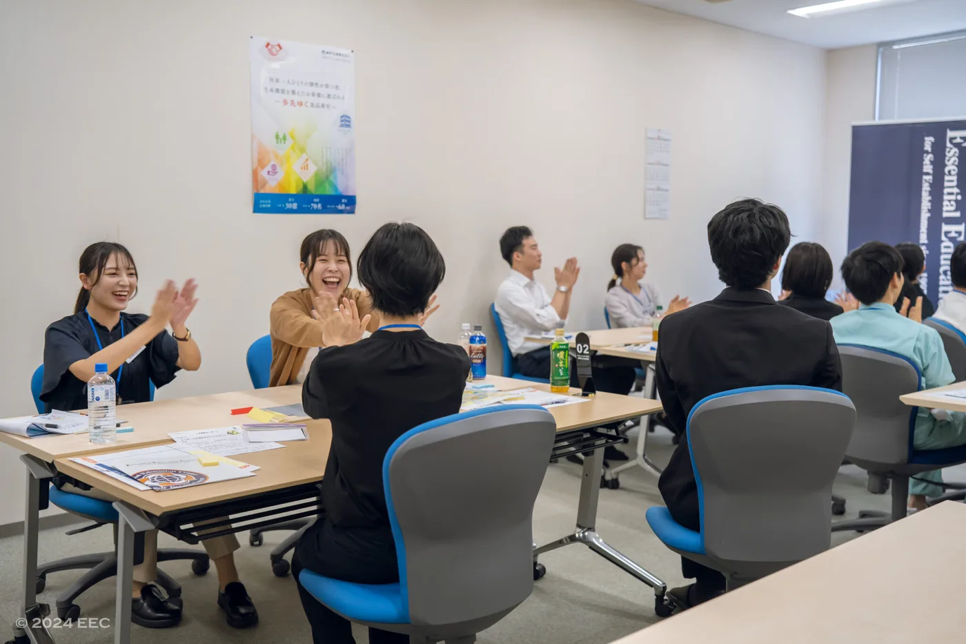 研修のグループワークで笑顔で拍手を交わす参加者たち。前のめりに関わり合う様子が、組織のエンゲージメント(活力・熱意)の高さを物語っている